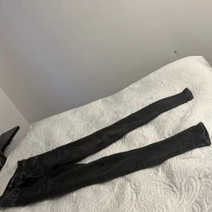 Svarta skinny jeans XS - Säljer ett par svarta skinny jeans i storlek XS. Jeansen har klassisk femficksdesign, dragkedja och knapp framtill. Snygg tvättad look och smal passform som sitter tight hela vägen ner. Perfekta till sneakers eller boots.