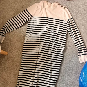 Randig långärmad klänning med knappar - Snygg långärmad klänning med svart och vit randigt mönster. Storlek S