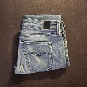 Replay ljusblå jeans med raka ben - Säljer ett par snygga ljusblå jeans från Replay med klassisk femficksdesign och diskreta slitningar. Jeansen har raka ben och normal passform, perfekt till vardagslooken. Materialet är mjukt jeans i bomull med lite stretch för extra komfort.