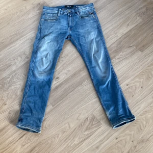 Replay Anbass ljusblå slim jeans - Snygga ljusblå jeans från Replay, modell Anbass Slim Fit. Jeansen har klassisk femficksdesign, slitningar och snygga detaljer på bakfickorna. Tillverkade i mjuk denim med en smal passform som sitter riktigt bra.