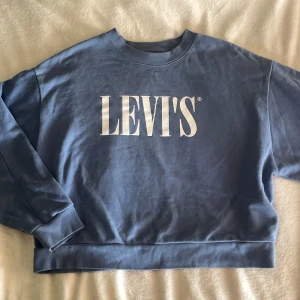 Sweatshirt Levis - Blå sweatshirt från Levi's i oversized modell med stort vitt logotryck framtill. Tröjan har rund halsringning, långa ärmar och breda muddar vid ärmslut och nederkant. Endast testad, pris kan diskuteras 