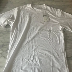 Vit t-shirt från Ljung  - Klassisk vit t-shirt från Ljung by Marcus Larsson i storlek M. T-shirten har rund halsringning och korta ärmar. Tillverkad i mjuk bomull för en skön känsla och enkel stil. Perfekt att matcha med jeans eller shorts.