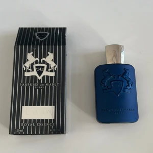 Parfums de Marly Layton 125ml - Lyxig parfym från Parfums de Marly, Layton Royal Essence. Flaskan är mattblå med silverfärgad kork och har en elegant relief med två hästar. Kommer i en svart och vit randig kartong. Volym: 125 ml.