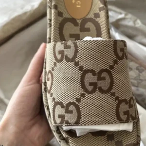 Beige sandaler från Gucci med GG-mönster - Snygga sandaler från Gucci i beige och brunt med det klassiska GG-monogrammet över hela skon. Öppen tå och bred rem framtill. Tillverkade i canvas med detaljer i skinn. Perfekta för dig som vill sticka ut med lyxig designerstil.