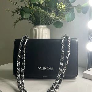 VALENTINO HANDVÄSKA - Säljer denna fina väskan! Den är svart med silver detaljer. Säljer pga den används för sällan och tycker den är för fin för att bara hänga i garderoben🤍