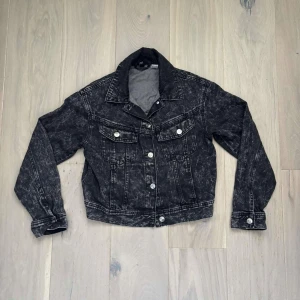 Croppad jeansjacka från H&M Divided  - Croppad svart acid wash jeansjacka från H&M Divided i storlek XS. Jackan är tillverkad i 100% bomull och har en snygg tvättad look som ger en edgy vibe.