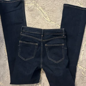 Mörkblå jeans från Zara, strl 34 - Snygga mörkblå jeans från Zara i storlek 34. Klassisk femficksmodell med kontrastsömmar och normal passform. Jeansen har midwaist och raka ben, tillverkade i mjukt bomullstyg med lite stretch för extra komfort.