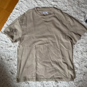 Beige t-shirt från Weekday - Snygg beige t-shirt från Weekday i mjuk bomull. Klassisk rund hals och korta ärmar. Lite större passform
