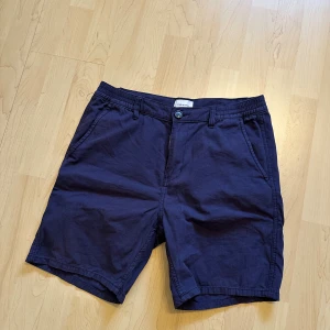 Mörkblå shorts från Studio Total - Snygga mörkblå shorts från Studio Total med klassisk passform och midwaist. Tillverkade i mjuk bomull, har fickor på sidorna och stängs med knapp och dragkedja. Perfekta för chill dagar under sommaren.