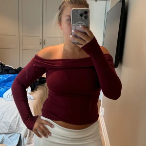 Vinröd offshoulder topp från Even&Odd - Säljer en vinröd offshoulder topp från Even&Odd med lång ärm och smickrande tight passform. Toppen har en bred kant över axlarna och är gjord i mjuk bomull. Perfekt för dig som gillar en stilren och trendig look.