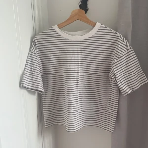 Randig t-shirt från H&M XS - Snygg t-shirt från H&M i storlek XS med horisontella grå och vita ränder. Modellen är kortärmad och har en klassisk rund hals med ribbad kant. Perfekt för dig som gillar enkel och clean stil. Materialet är mjuk bomull som känns skönt mot huden.