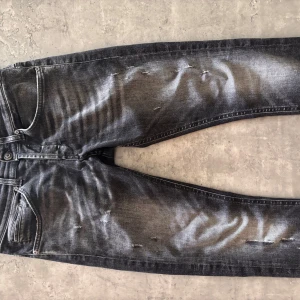 Slim jeans från Dondup - Snygga svarta slim jeans från Dondup med slitningar och tvättad look. Jeansen har klassisk femficksmodell, coola detaljer på knapparna och Dondup-läderpatch bak. Perfekta för dig som gillar en edgy och modern stil. Inga defekter, hör av dig ifall du har funderingar!