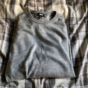 Grå stickad tröja från Uniqlo XS - En stilren grå stickad tröja från Uniqlo i storlek XS. Tröjan har rund halsringning, ribbade muddar och är långärmad. Perfekt för lager-på-lager och funkar till många olika outfits. Enkel och klassisk design som aldrig går ur tiden.