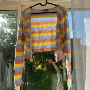 Randig croppad kofta från Boohoo - Superfin croppad kofta från Boohoo med färgglada ränder i gult, ljusblått och rostbrunt. Stickad i ett tunt material med långärmad passform och öppen framtill. Perfekt för dig som gillar färg och vill sticka ut lite extra.