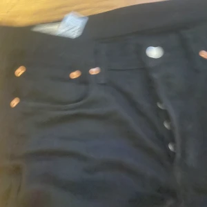 Svarta Levi's 501 jeans W32 L30 - Säljer ett par svarta Levi's 501 jeans med klassisk straight fit och knappgylf. Byxorna har fem fickor, kopparfärgade nitar och den ikoniska läderpatchen bak. Passar dig som gillar tidlös stil och vill ha jeans som funkar till allt.