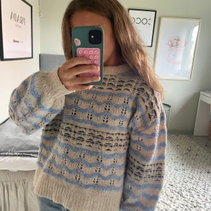 Beige och blå stickad tröja ONLY XS - Supermysig stickad tröja från ONLY i beige med blå och mörkblå vågiga ränder. Tröjan har ett luftigt, hålmönstrat stickat mönster och ribbade muddar. Perfekt för lager-på-lager och chill dagar.