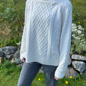 Vit stickad tröja med flätmönster - Supermysig vit stickad tröja med grovt flätmönster och ribbade muddar. Tröjan har en relaxed passform, rund halsringning och långa ärmar. Perfekt för kyliga dagar när du vill vara både varm och snygg. Sparsamt använd, så fint skick men har några noppor. Går lätt att ta bort med noppmaskin. Kan fixa det om köparen önskar.