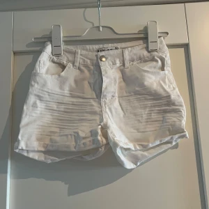 Vita jeansshorts från Amisu - Snygga vita jeansshorts från Amisu med klassisk femficksdesign och uppvikta benslut. De har normal passform och stängs med dragkedja och knapp. 