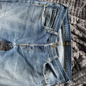 jeans från Lee - Snygga blå jeans från Lee med klassisk femficksdesign och raka ben. Jeansen har ljus tvätt med slitningar och kontrastsömmar i gult. Tillverkade i bomull för en skön och avslappnad känsla. 