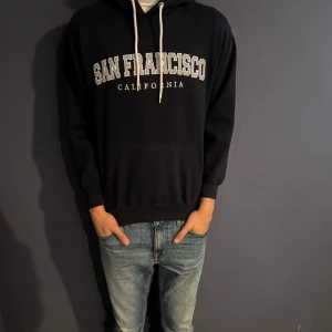 Mörkblå hoodie med San Francisco-tryck - Säljer denna mörkblå San Francisco hoodien. Hoodien är köpt i usa för ungefär 599kr. Säljer den nu för 349 eftersom den knappt är använd och är i topp skick. Hör av er vid frågor eller funderingar!