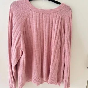 Rosa ribbad stickad tröja - Mysig rosa stickad tröja med ribbade detaljer och rund halsringning. Tröjan har en loose passform och långa ärmar, perfekt för att hålla sig varm under kyliga dagar. Enkel och stilren design som är lätt att matcha.