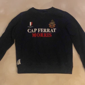 Mörkblå sweatshirt från Morris - Mörkblå sweatshirt från Morris med broderad text 'Cap Ferrat Morris' i vitt och rött framtill. Det är en perfekt tröja till dig som vill ha en skön tröja att ha i vardagen.Tröjan är i superbra skit då jag knappt har andvänt den.                                                                  Skriv för mer info Mvh Valter🤩