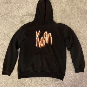 Svart Korn hoodie - Svart hoodie med Korn. Perfekt för dig som gillar bandmerch och vill ha en skön, avslappnad stil.