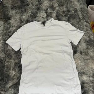 Vit t-shirt från H&M med tryck - Vit t-shirt från H&M i storlek S med minimalistiskt tryck 'L'ATELIER ARCHIVES Paris' på bröstet. Klassisk rund hals och korta ärmar. Tillverkad i mjuk bomull för en skön känsla och enkel stil.