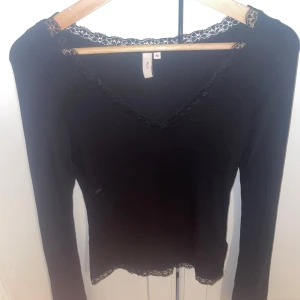  Nelly tröja - Svart långärmad topp från Nelly i storlek XS. Toppen har v-ringning och är dekorerad med fin spets längs halsringning och nederkant. Snygg och enkel modell som är lätt att matcha till olika looks aldrig använd stora i storlek så passar xs-s 