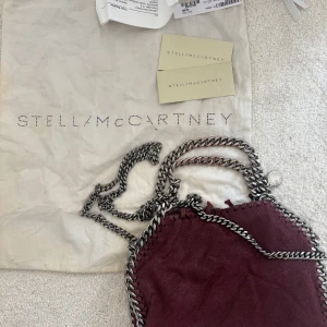Vinröd axelväska från Stella McCartney - Säljer en vinröd axelväska från Stella McCartney falabella mini om jag minns rätt. Den är sliten därav priset. Har alla kvitton äkthetsbevis och dustbag kvar!  Nypris är 9000kr