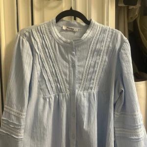Ljusblå blus med spetsdetaljer Vitrine - Supersöt ljusblå blus från Vitrine med fina spetsdetaljer och knappar framtill. Blusen har lång ärm med dekorativa sömmar och en lätt strukturerad bomullskänsla. Perfekt för dig som gillar söta och luftiga plagg. Står stolen M men mer som en S. Skriv privat för bilder på. Nypris 400.