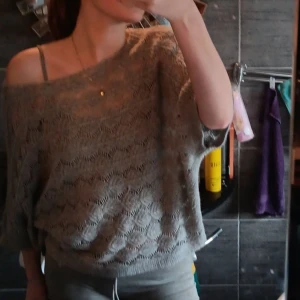 Grå stickad topp från Coal & Honey - Grå stickad topp från Coal & Honey med snyggt hålmönster och lös passform. Tröjan har bred halsringning som kan bäras offshoulder och trekvartsärmar. Perfekt för lager-på-lager och chill vibes.