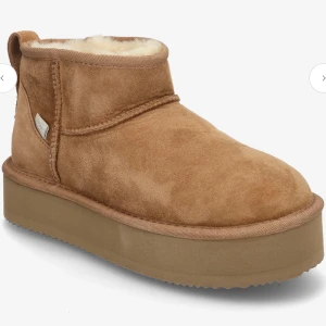 Beige bruna uggs   - Säljer ett par beige bruna uggs i mocka med fluffigt foder och platt sula. Skorna har rund tå, låg skaft och bred platå. Perfekta för kalla dagar och ger en chill vibe till din outfit. Skorna är använda en gång och ser som nya ut! Ny pris 720