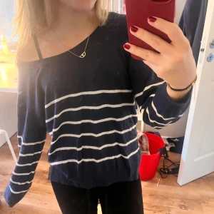 Off shoulder stickad  - En off shoulder stickad tröja som är mörklblå med vita ränder. 