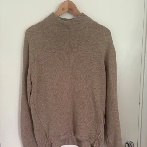 Daniele fiesoli tröja  - Beige stickad tröja från Daniele Fiesoli med hög ribbad krage och långa ärmar. Tröjan har en klassisk och enkel design i mjukt material, perfekt för lager-på-lager. Passar dig som gillar stilrena och tidlösa plagg.