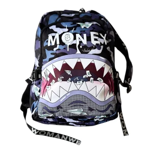 Back pack  - Cool ryggsäck från Womanwe med blå, lila och svarta camouflage-mönster och ett stort hajmotiv med tänder och sedlar. Texten 'MONEY' syns på framsidan. Justerbara axelband med tryckt logga och flera fack med dragkedja. Perfekt för dig som vill sticka ut.