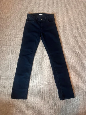 Mörkblå skinny jeans från Wrangler - Snygga mörkblå jeans från Wrangler med klassisk femficksdesign och tydliga W-detaljer på bakfickorna. Modellen är skinny med smal passform och normal midja. Jeansen är tillverkade i stretchig denim för extra komfort.