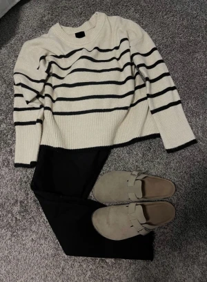 Beige och svart randig stickad tröja - Snygg stickad tröja i beige med svarta ränder. Tröjan har rund hals och långa ärmar med ribbade muddar och nederkant. 