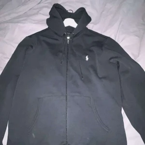 Svart hoodie från Ralph Lauren - Svart zip hoodie från Ralph lauren. Aldrig använd, bara tagit bort lapparna. Köpt på johnells, nypris 2399, mitt pris 799. Har kvittot kvar. Skriv om ni har funderingar!