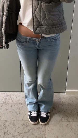 Ljusblå låga bootcut jeans - Säljer ett par ljusblå bootcut jeans med låg midja och snyggt rosa broderi på bakfickan. Från Nelly!