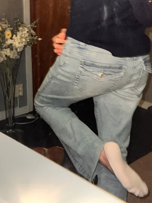 Jeans blåa ginatricot - Säljer ett par ljusblå jeans med bootcut passform och snygga fickor med lock och knapp bak. Jeansen har låg midja. De är som nya, köpte för 399kr säljer pga jag rensar min garderog. De har strl 38 men skulle säga de är mer som 34. 😉🩷