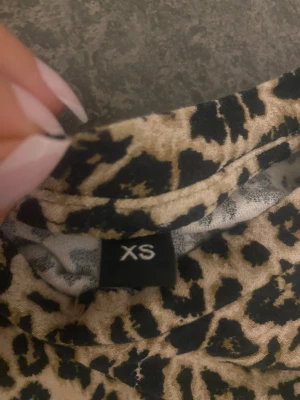 Leopardmönstrad kort klänning XS - Säljer en snygg kort klänning i leopardmönster med beige och svarta toner. Klänningen har rund halsringning och lätt puffade axlar. Perfekt för dig som vill sticka ut med ett djurmönster. Materialet känns mjukt och stretchigt.