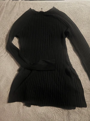 Svart ribbad stickad tröja - Svart stickad tröja med lång ärm och ribbat mönster. Modellen är kroppsnära och har en enkel, stilren design som passar perfekt till säsongens outfits. 