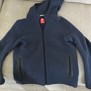 Mörkblå Nike tech fleece - Hej säljer ni min Nike tech fleece för att råka köpa den lite för liten. Den är knappt använd har använt den max 2 gånger. Det finns inga skador och priset kan diskuteras vid snabb affär.