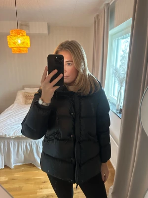 Svart pufferjacka med huva - Säljer en svart pufferjacka från peak, med dragkedja framtill. Snygg och enkel att matcha med olika outfits.