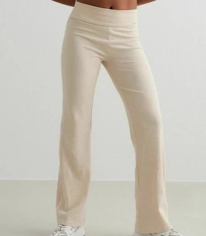 Beige ribbade mjukisbyxor Aim'n M - Säljer ett par beige ribbade mjukisbyxor från Aim'n i storlek M. Byxorna har hög midja och är tillverkade i mjukt bomullsmaterial med lite stretch för extra komfort. De har en straight passform och diskret metallmärke framtill i midjan.