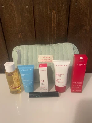 Clarins necessär med lip perfector, beauty flash balm, total eye lift, cleansing oil, hydra essentiel cream och mascara - Clarins necessär med lip perfector, beauty flash balm, total eye lift, cleansing oil, hydra essentiel cream och mascara. Allt är nytt och oöppnat.  Clarins lip perfector 24 fuschia glow 5 ml Clarins total eye lift 7 ml Clarins beauty flash balm 30 ml Clarins total cleansing oil 50 ml Clarins hydra-essentiel moisturizer quenches silky cream 15 ml Clarins supra lift & curl mascara 01 intense black  3 ml
