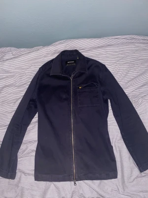 Mörkblå overshirt från Lyle & Scott - Snygg mörkblå overshirt från Lyle & Scott med dragkedja framtill och klassisk krage. 