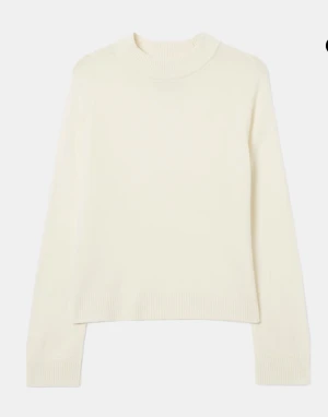 Vit stickad tröja med rund hals - Snygg vit ull tröja med rund hals och långa ärmar. Tröjan har ribbade muddar vid hals, ärmslut och nederkant för en clean look. Perfekt att matcha med jeans eller kjol för en enkel och fräsch stil.