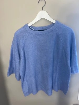 Ljusblå stickad topp från 157 - Säljer en ljusblå stickad topp från 157 i storlek XS. Toppen har rund hals, korta ärmar och är tillverkad i ett mjukt stickat material som känns skönt mot huden. Perfekt för dig som gillar enkel och clean stil med en touch av färg.